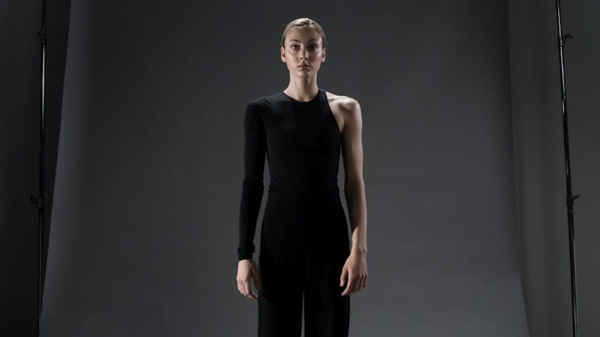 A person in a calm, focused yoga pose against a dark background.